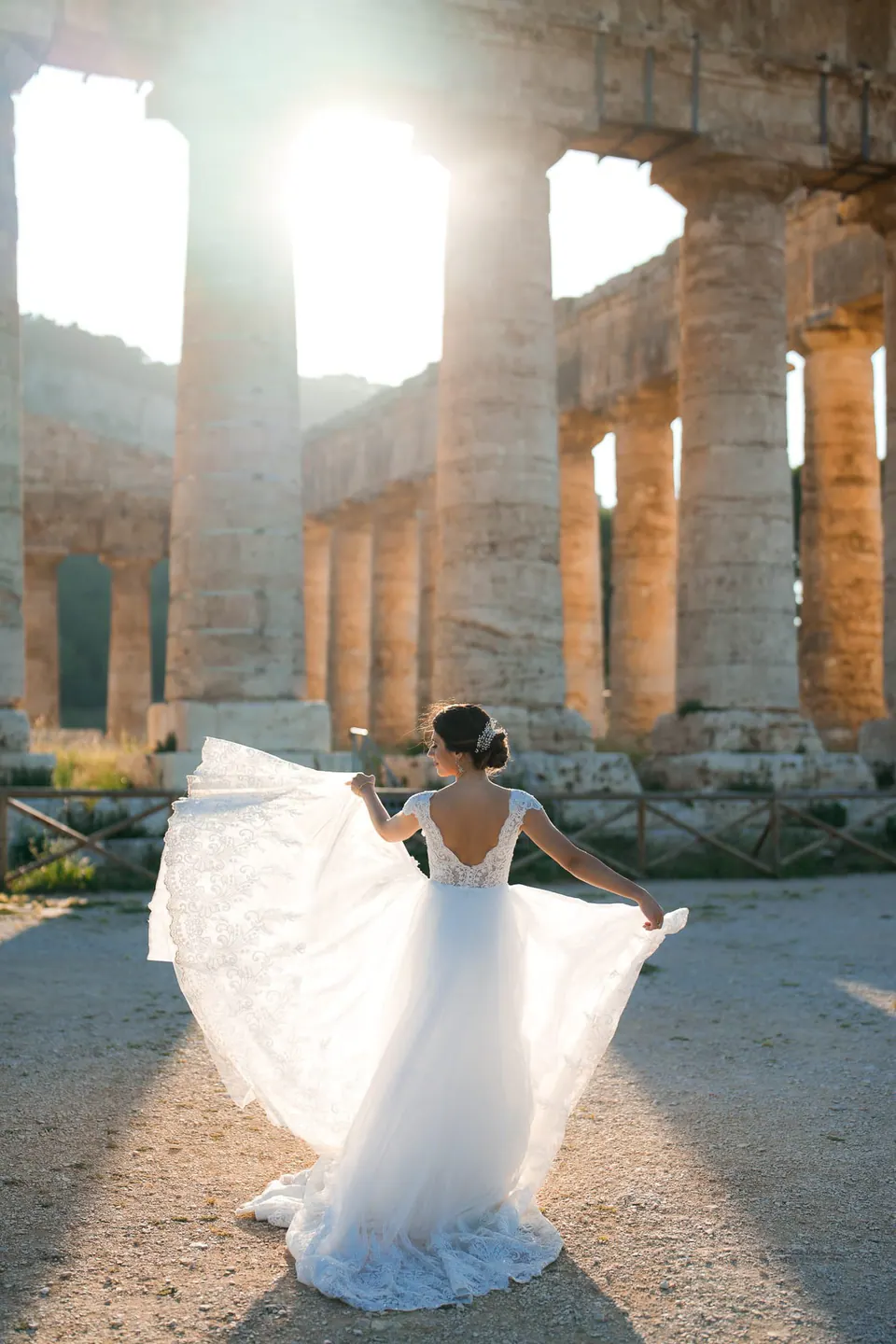 Bride twirling her gown among the columns of an ancient Greek temple in Sicily.