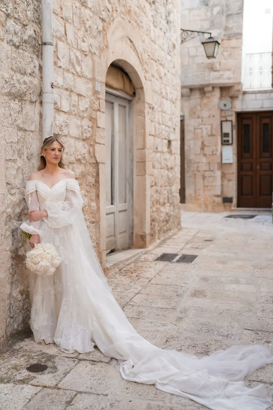 La novia camina junto a muros de piedra rústicos, boda en el sur de Italia.