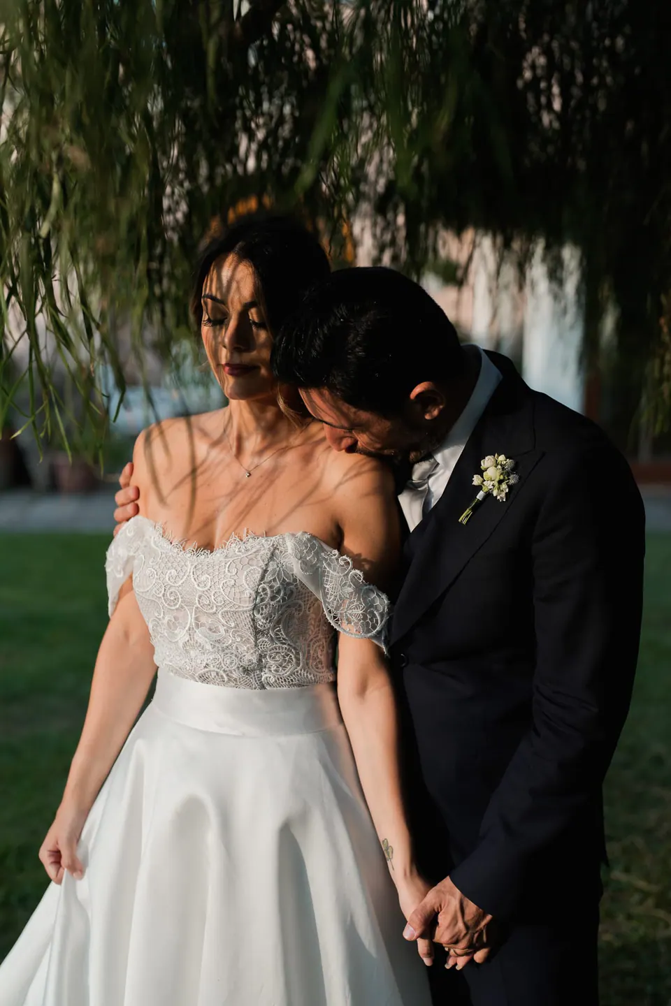 Bride and groom holding hands under a tree in soft evening light