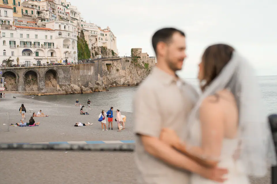 The couple face to face on the seafront, the beach and the town of Amalfi out of focus behind them.