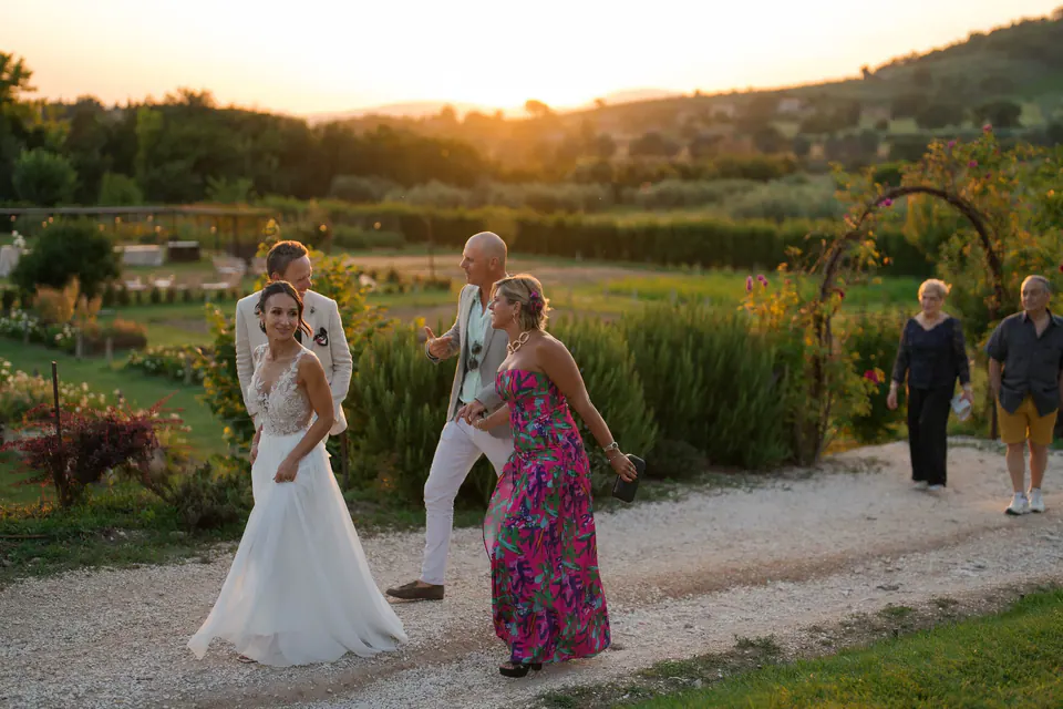 Bride with guests on a path at sunset