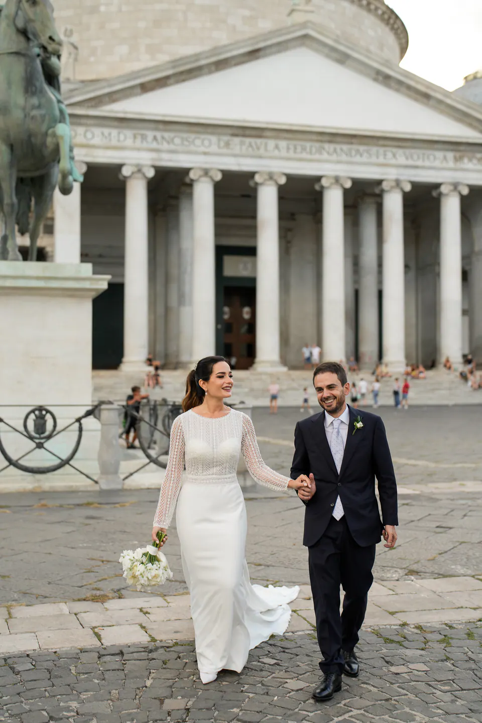 Bride and groom walking hand in hand through Naples’ historic center.