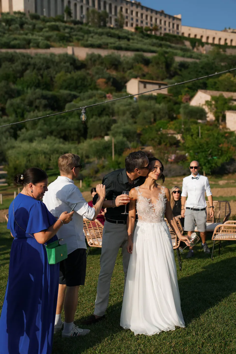 Bride with guests on the lawn, Assisi on the hill above