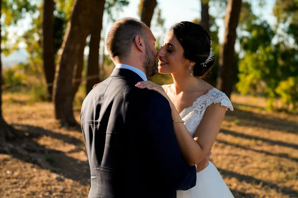 Bride and groom embracing among pine trees at sunset