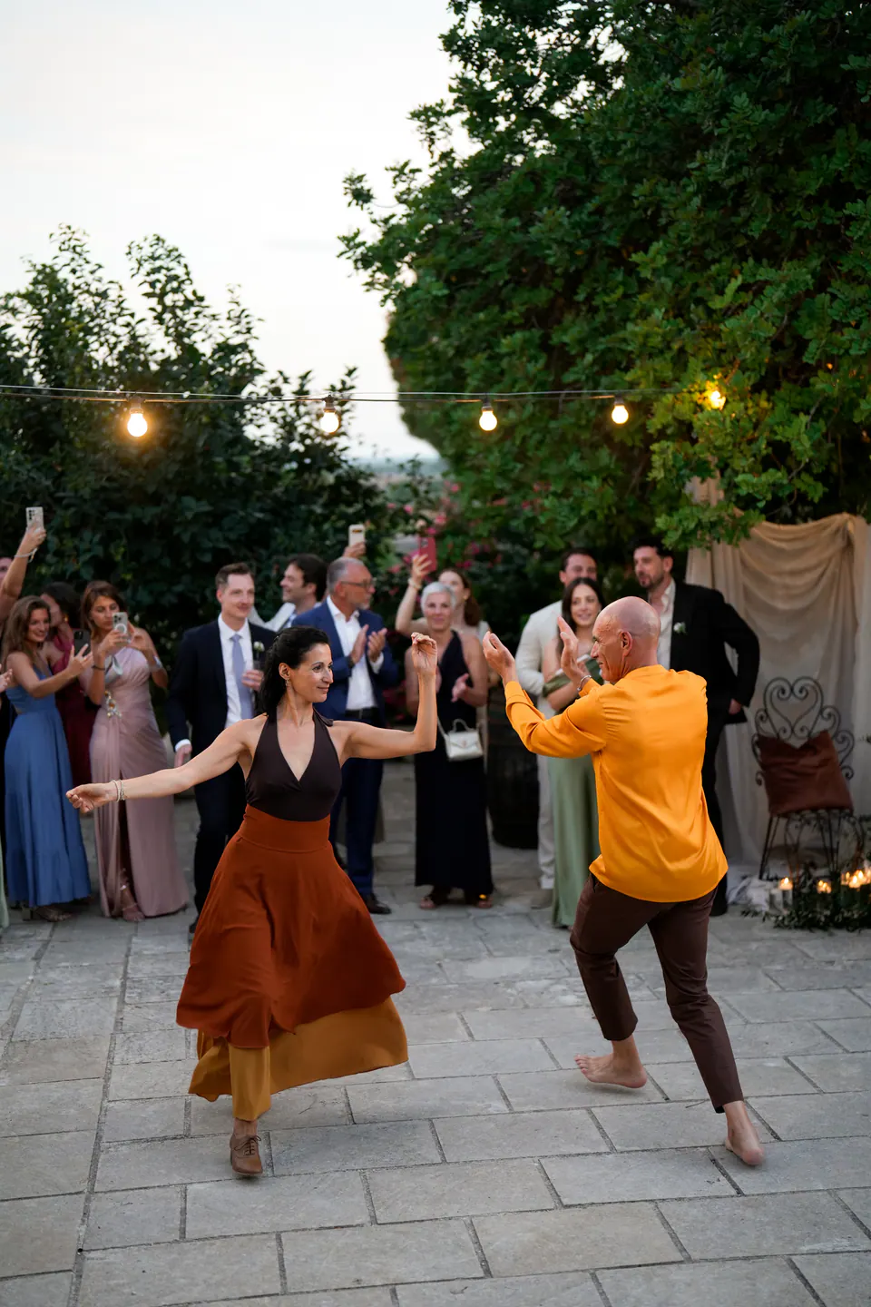Una ballerina di pizzica che volteggia nel cortile mentre gli invitati applaudono e riprendono.