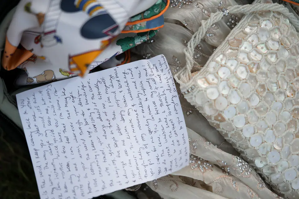 The handwritten vows lying on the lace of the dress and a beaded bag.