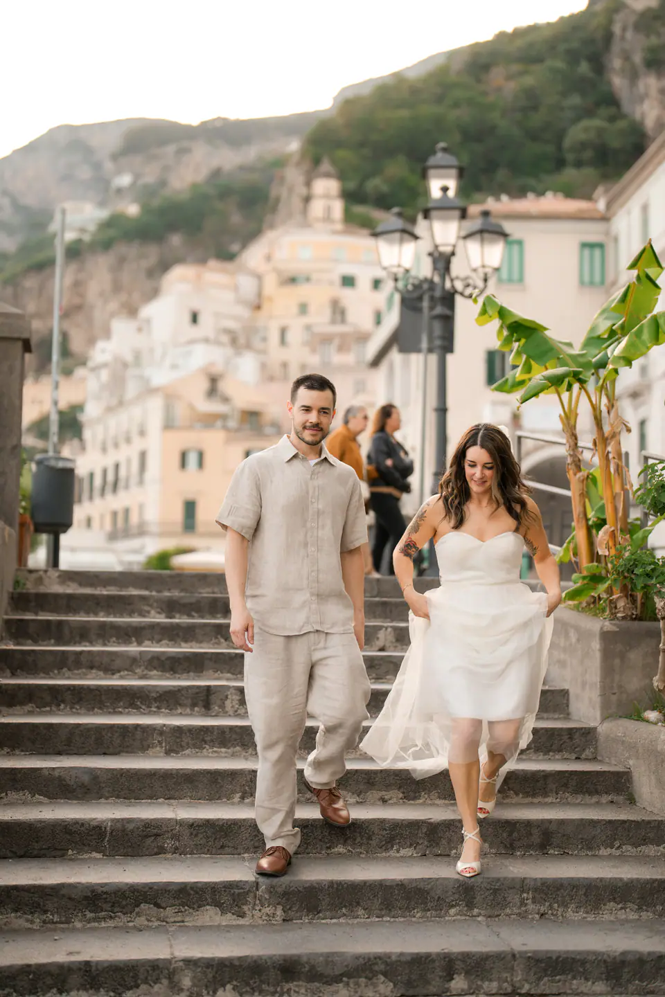 Couple walking down a stone staircase among the houses of Amalfi.