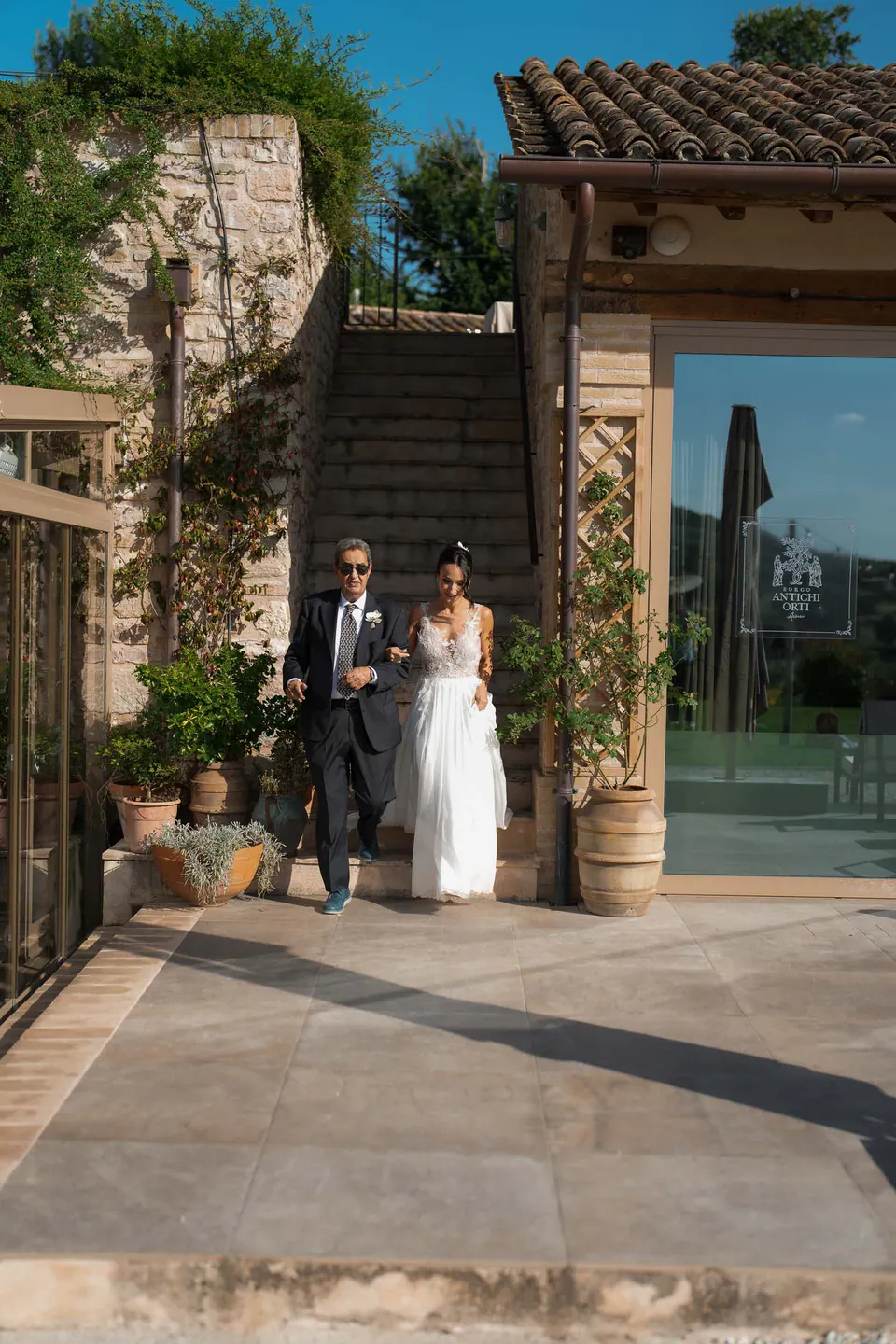 Bride walking out of an arched doorway with an older man