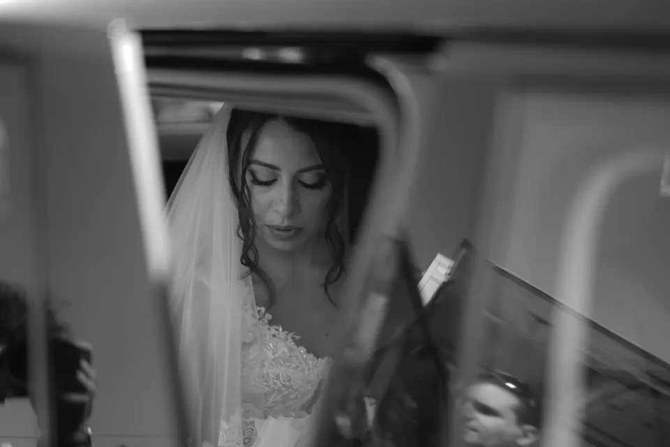 Black and white photo of the bride reflected in the car mirror on the way to the church.