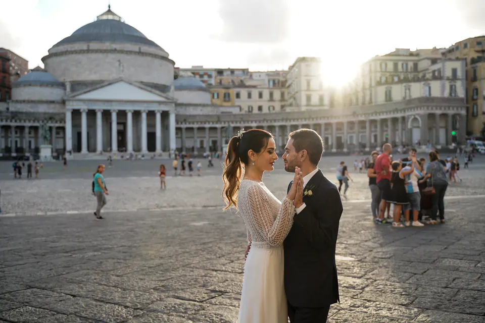 Bride and groom facing each other in Piazza del Plebiscito at sunset.