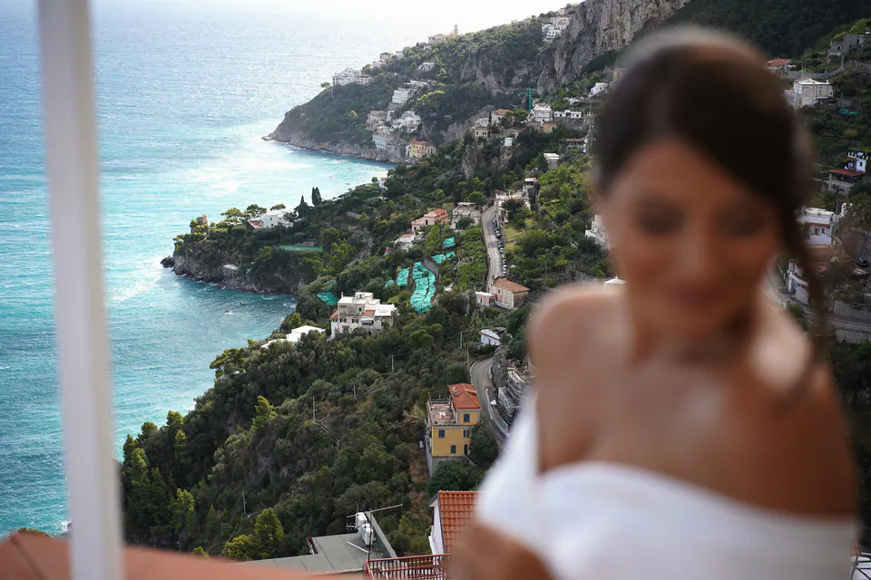 Bride softly out of focus, the Amalfi coastline far below.