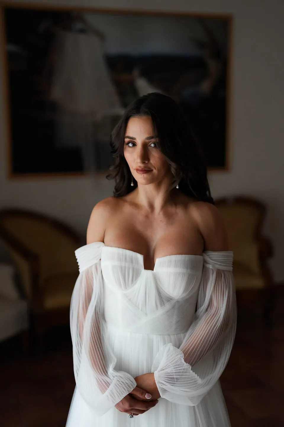 Die Braut im schulterfreien Kleid mit transparenten Ärmeln, Porträt im weichen Licht der Villa.