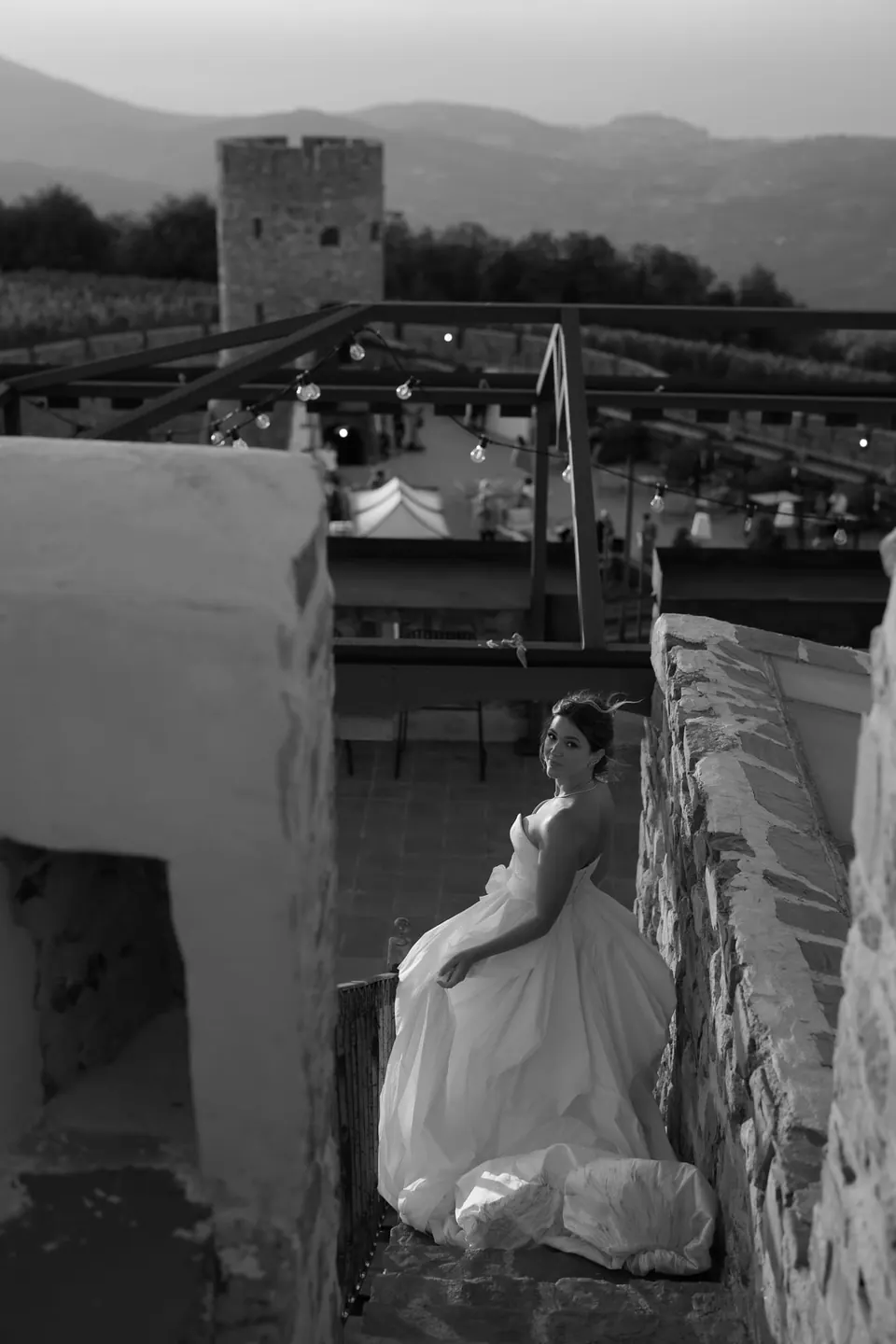 Foto in bianco e nero della sposa seduta sui bastioni del castello, una torre in lontananza.