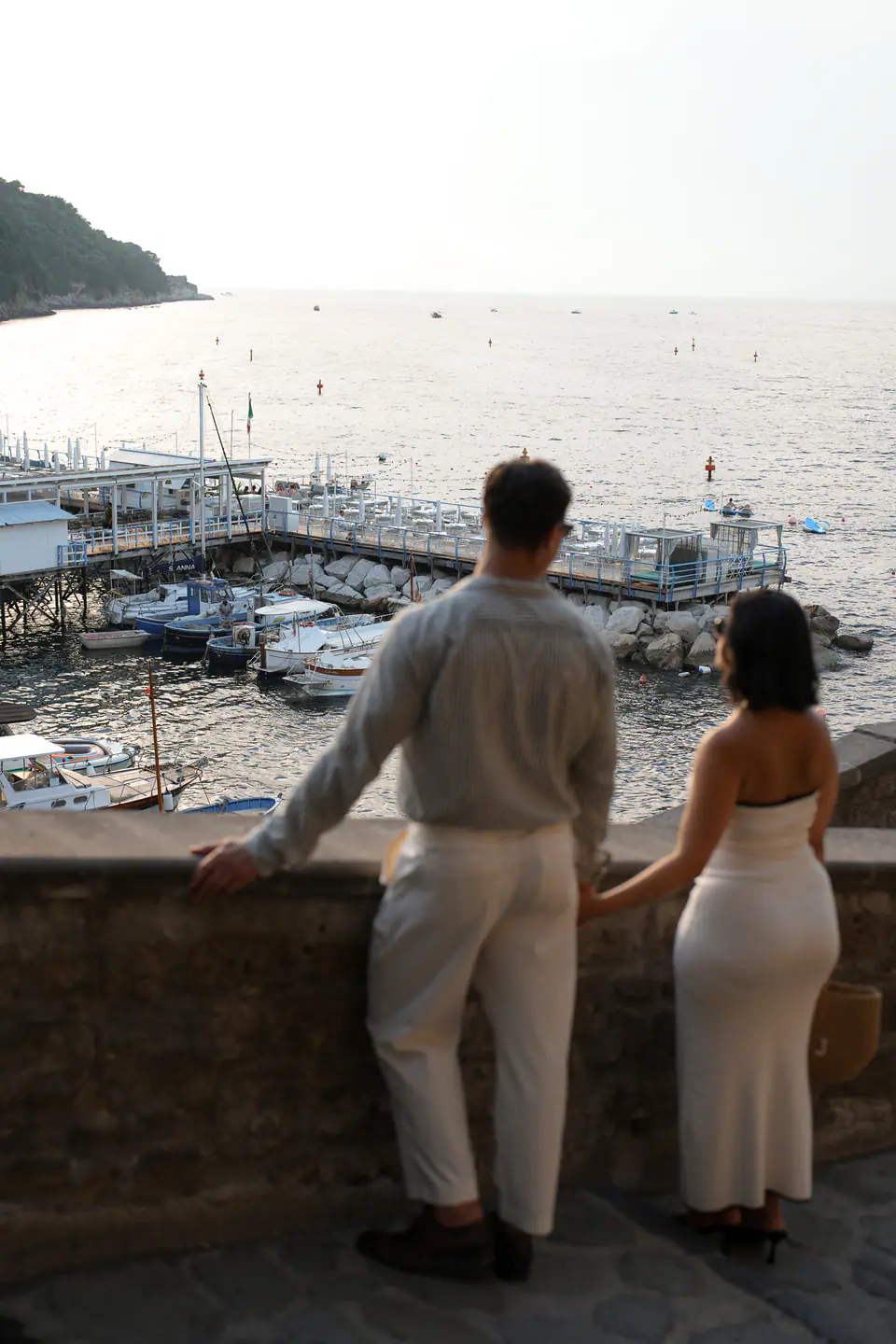 Couple from behind looking down at the boats in the harbour.