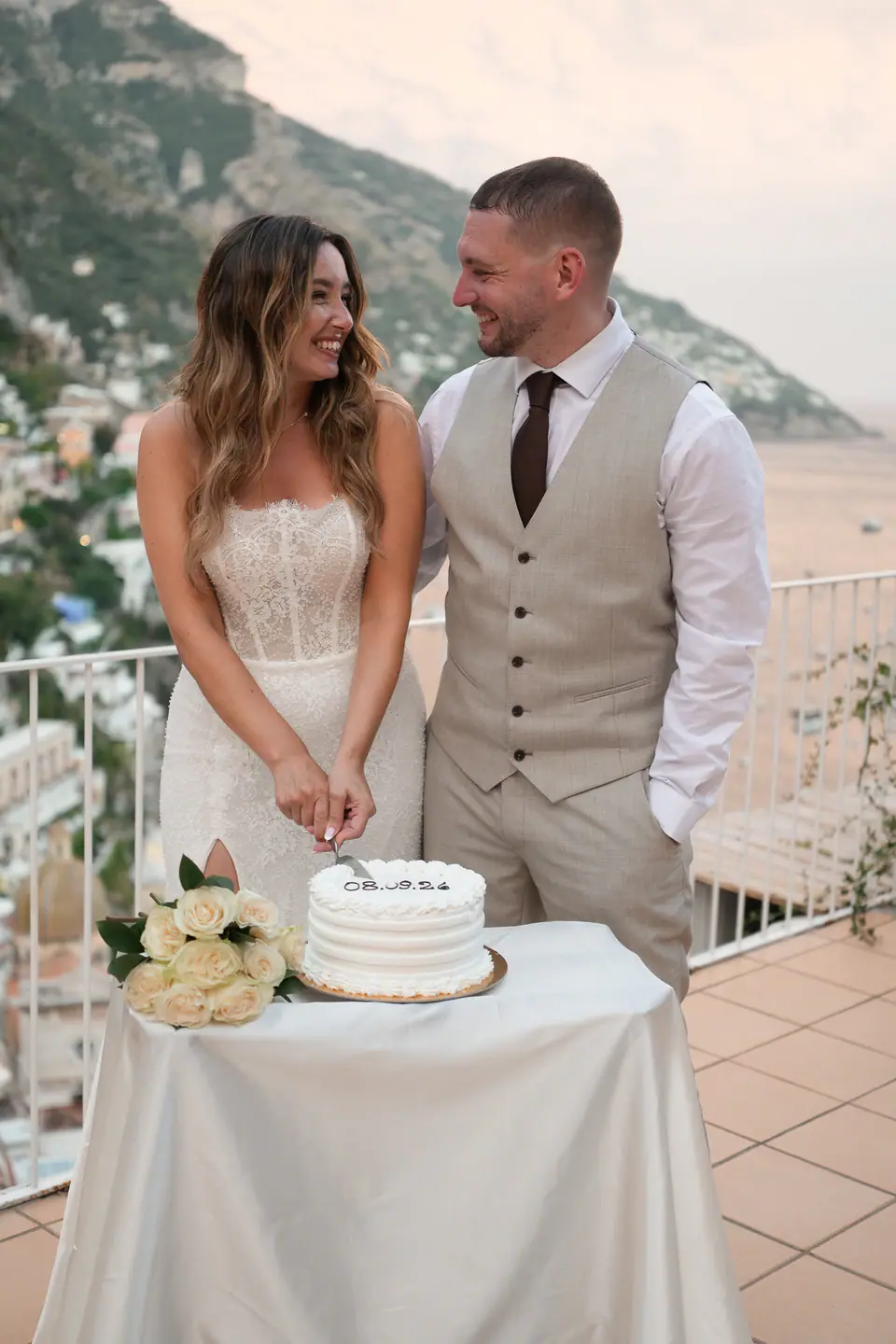 Couple cutting their cake on the terrace at dusk.