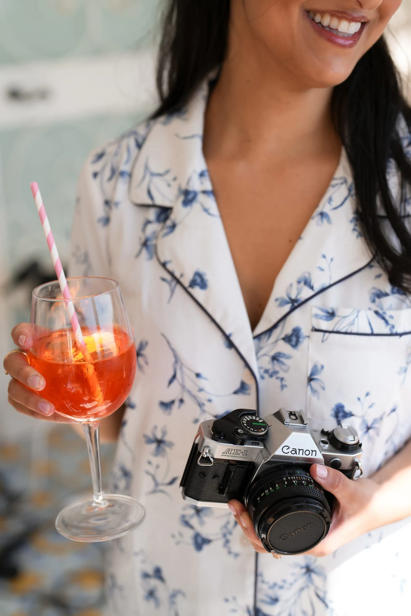Eine Brautjungfer im geblümten Pyjama mit Spritz und analoger Kamera.