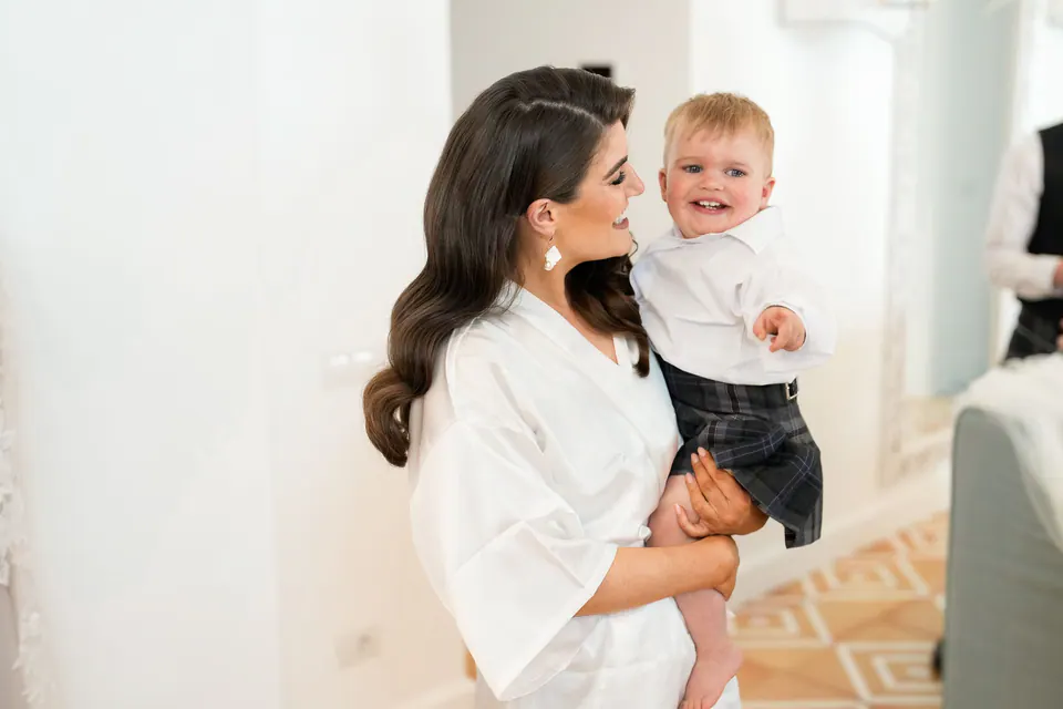 La sposa tiene in braccio con affetto il suo bambino, tenero momento di famiglia prima del matrimonio.