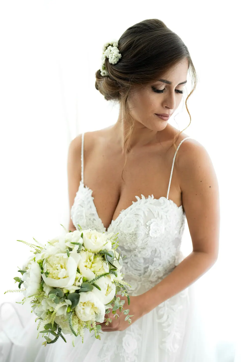 Bride holding her bouquet of white roses, flowers in her hair.