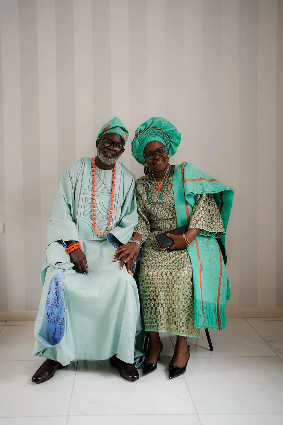 Dos mayores con traje tradicional nigeriano y gele sentadas juntas en la villa.
