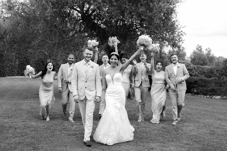 Le cortège court sur la pelouse, bouquets levés, en noir et blanc.