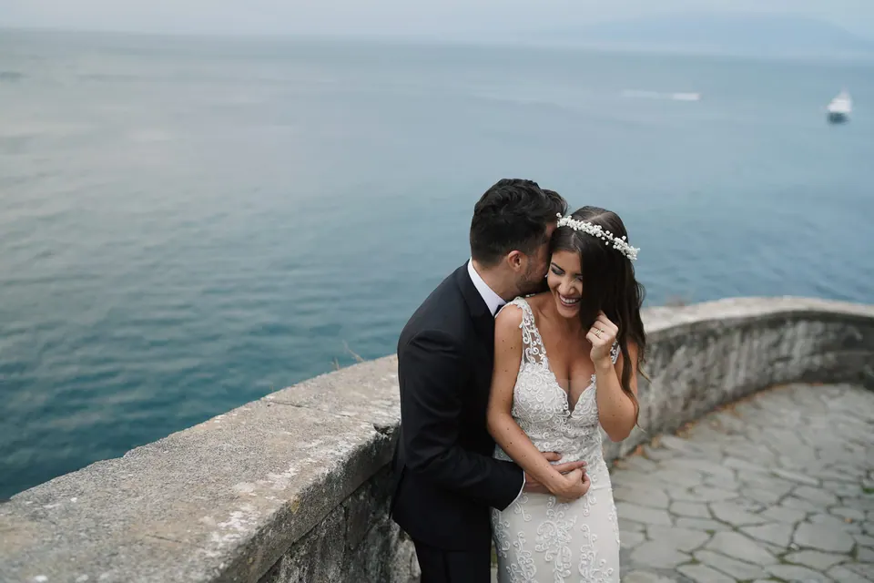 Bride and groom by the curved stone wall above the sea in Sorrento.