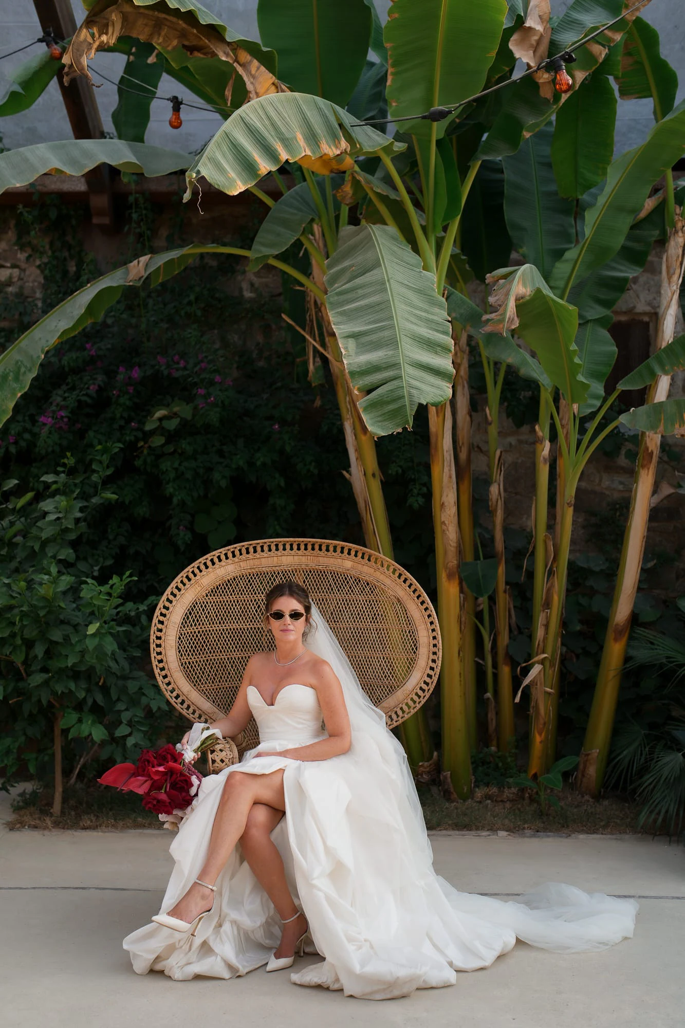 La novia con gafas de sol relajada en el sillón pavo real, con las piernas cruzadas.