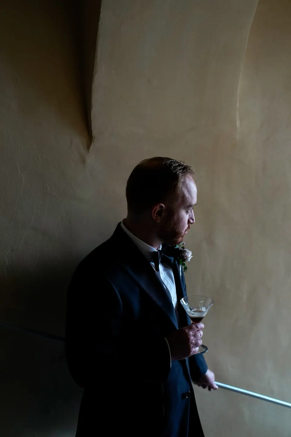 Groom walking down a hotel corridor in soft light.