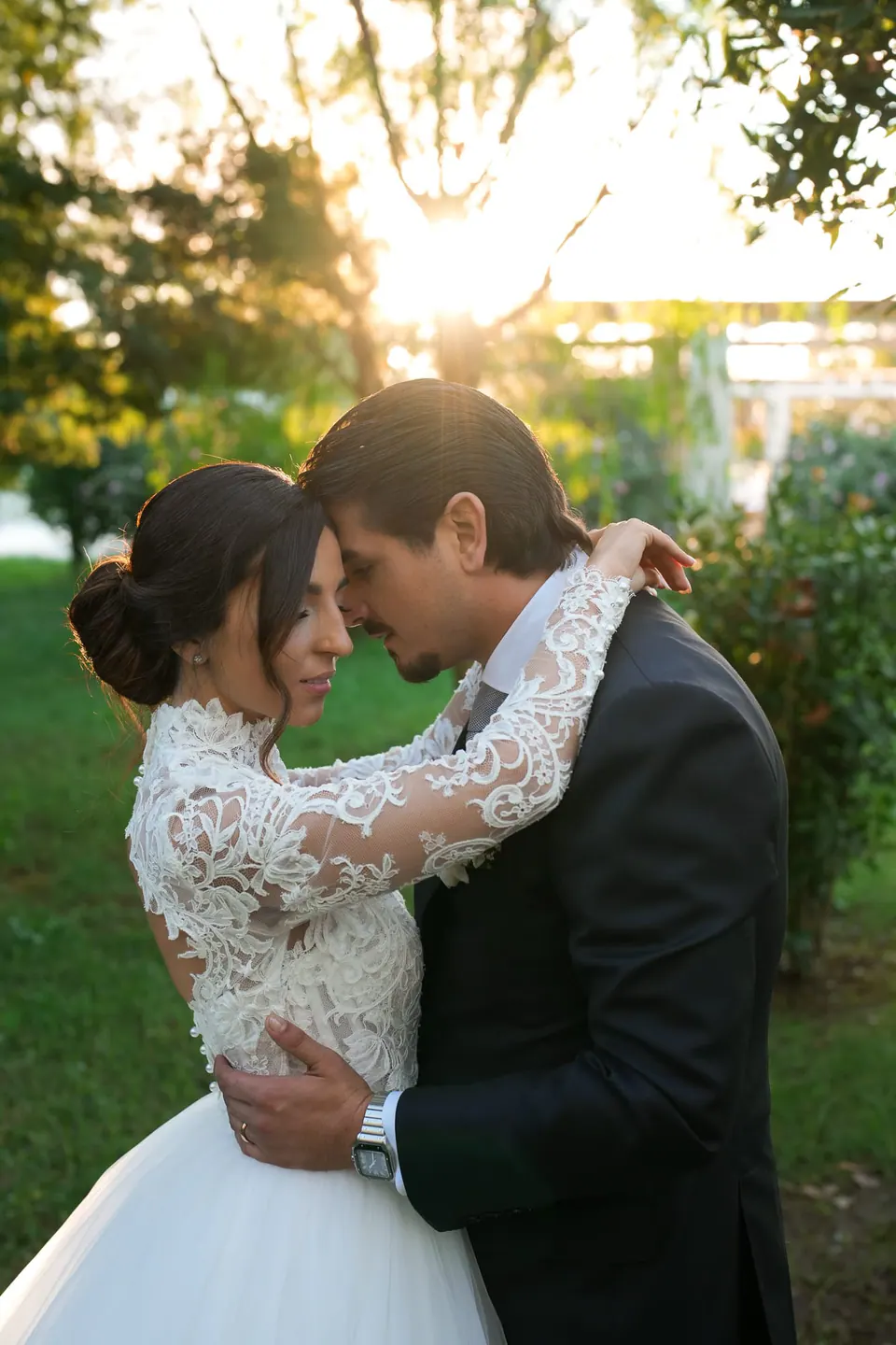 Bride and groom sharing a tender kiss outside under golden sunlight, authentic moment of love in Caserta, Italy.