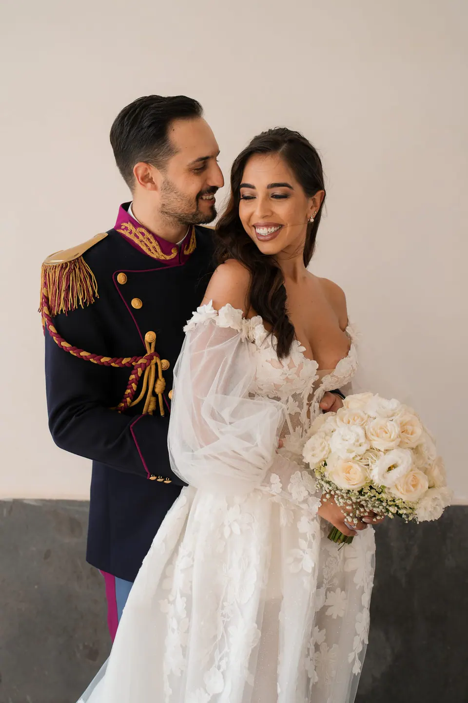Groom in military dress uniform and the smiling bride with her bouquet.