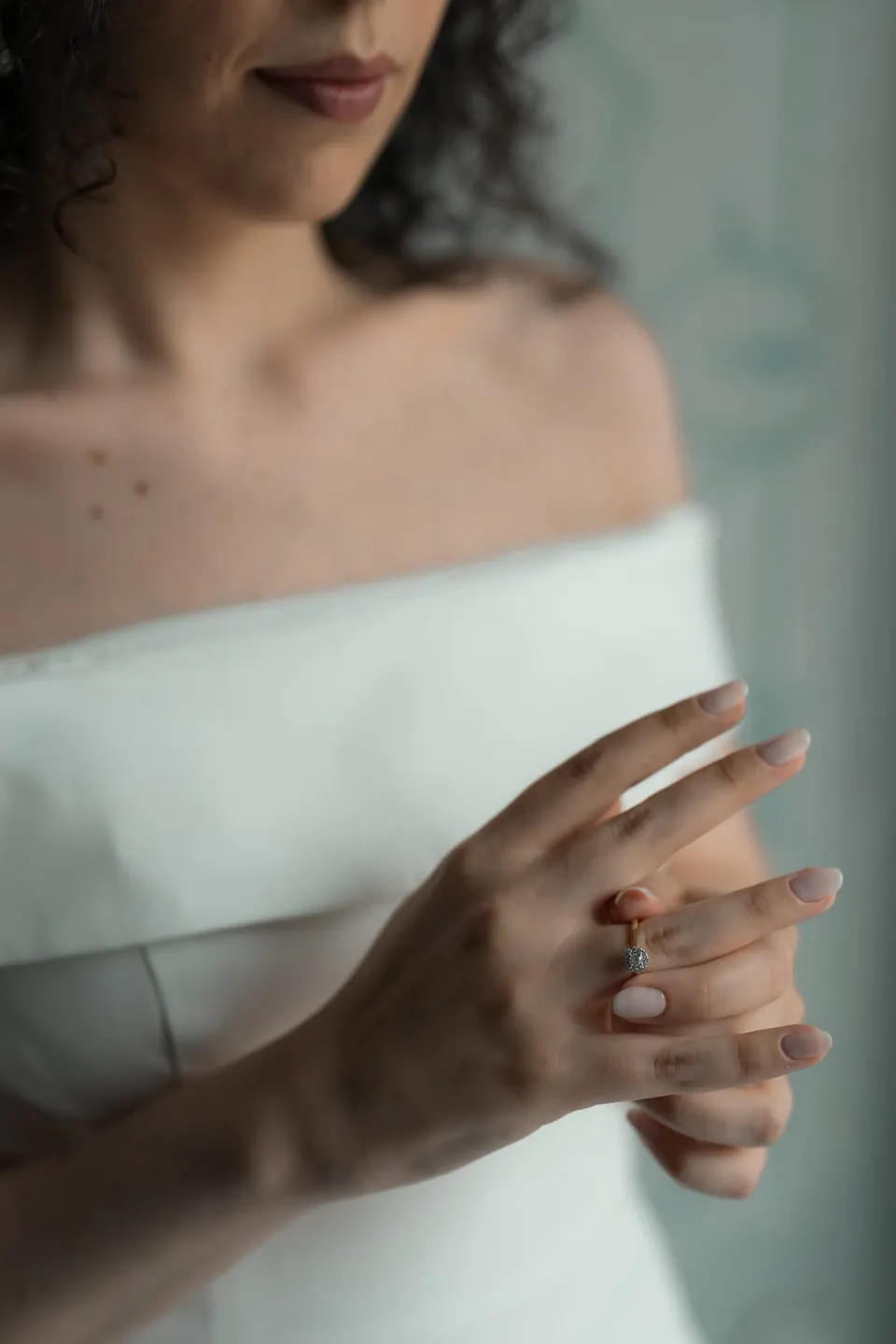 Primer plano del escote de hombros descubiertos de la novia y sus manos sujetando la tela.