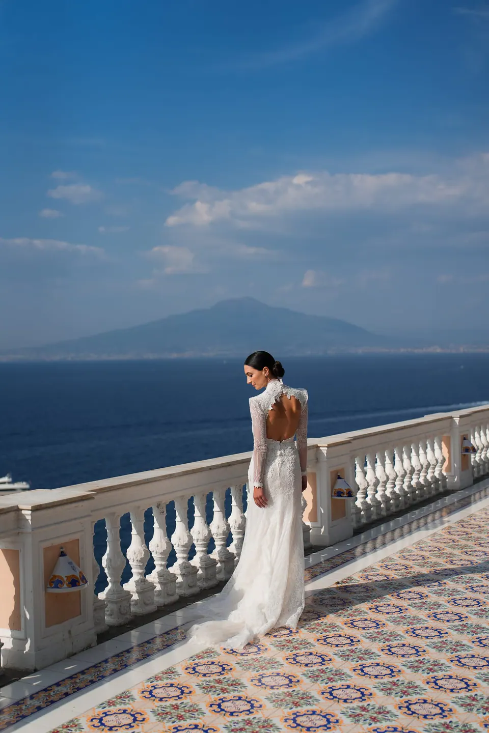 Bride at the majolica terrace balustrade of Parco dei Principi, Vesuvius across the gulf.