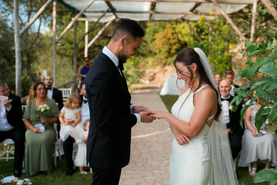 Exchange of rings under the pergola, family and friends looking on.