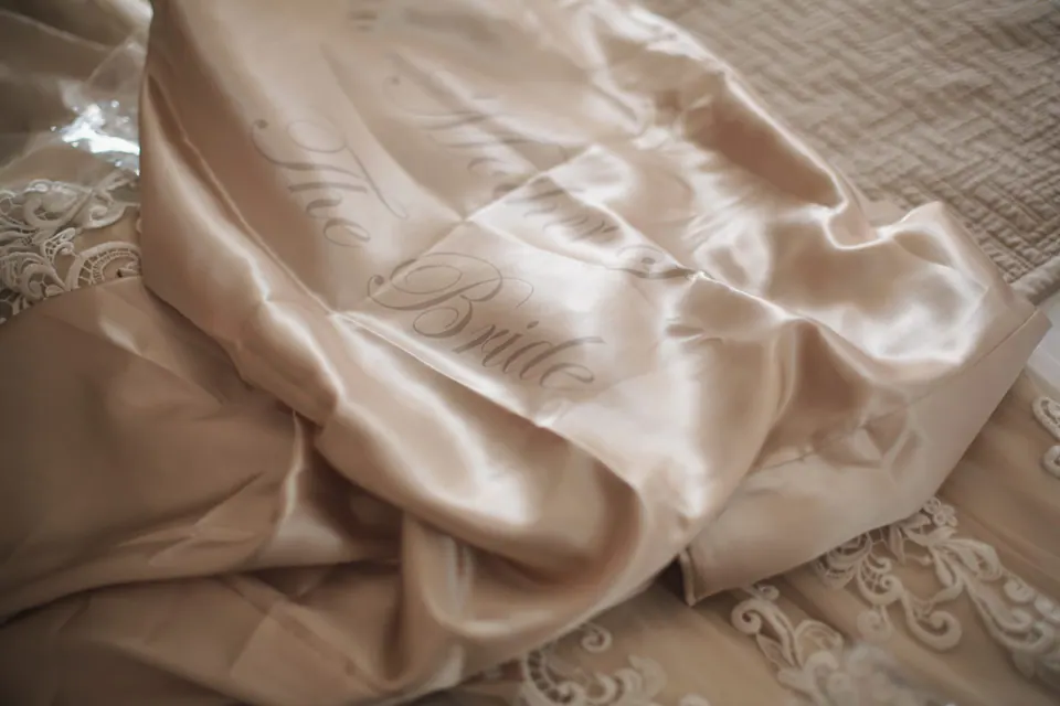Folds of a champagne satin robe with lace trim.