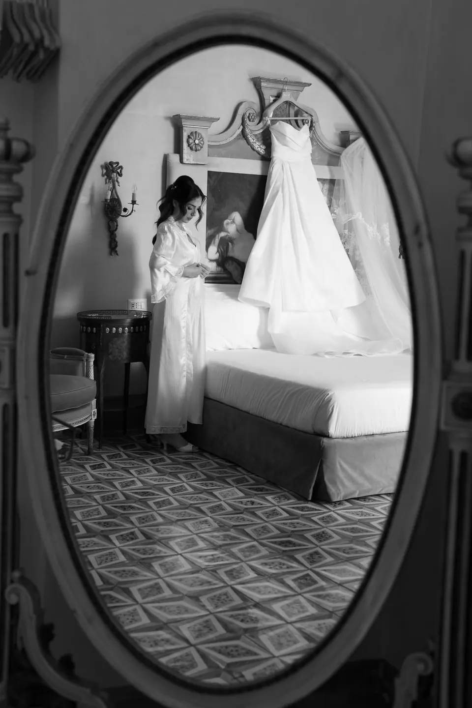 Reflejo en blanco y negro de la habitación y el vestido colgado en un espejo ovalado.