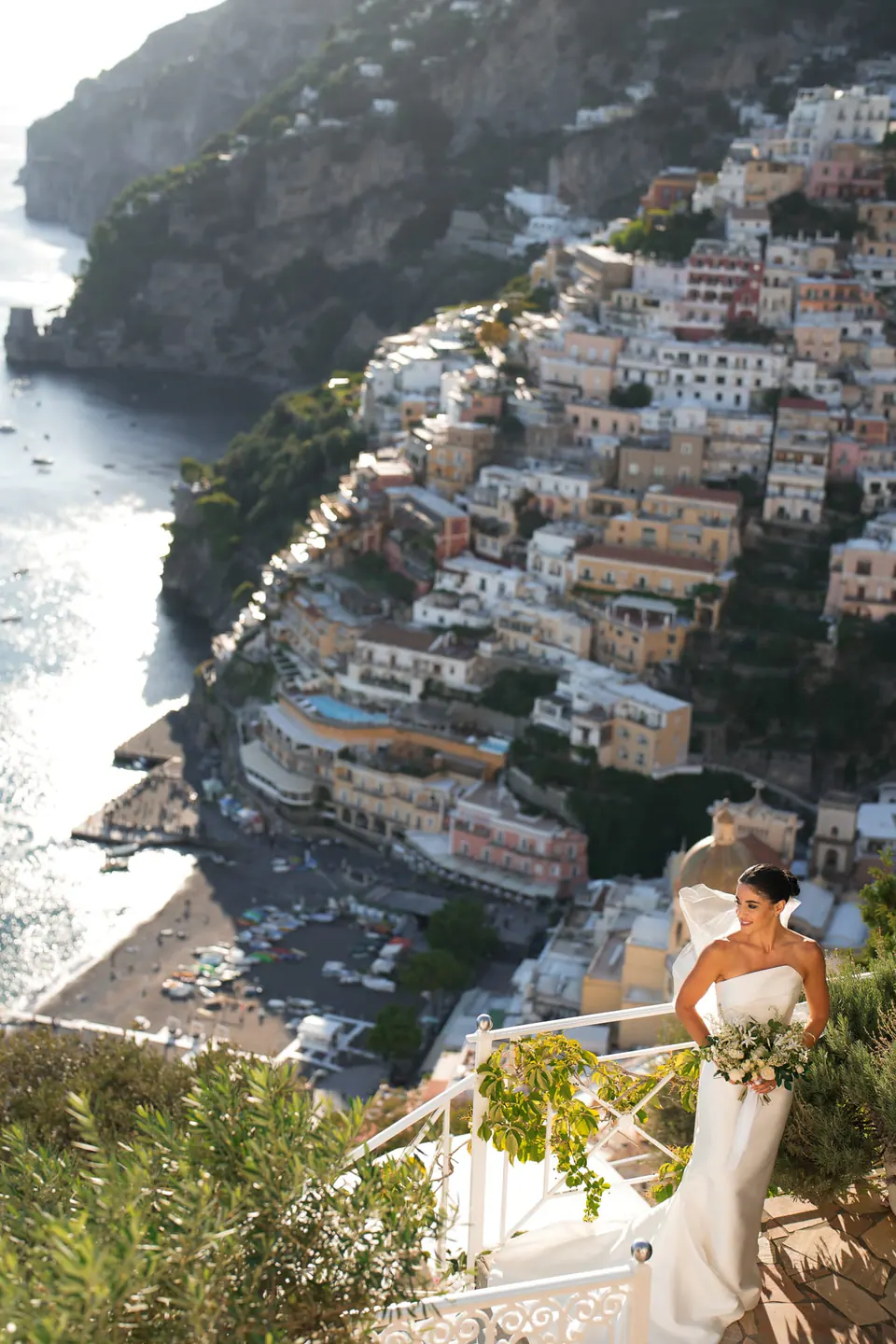 Bride on a terrace high above Positano, among flowering plants.