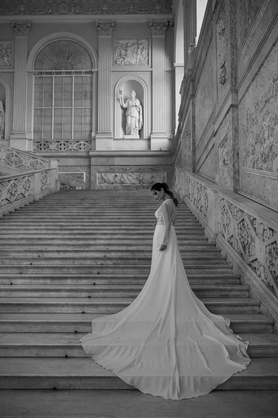 Bride walking up a marble staircase in golden light.