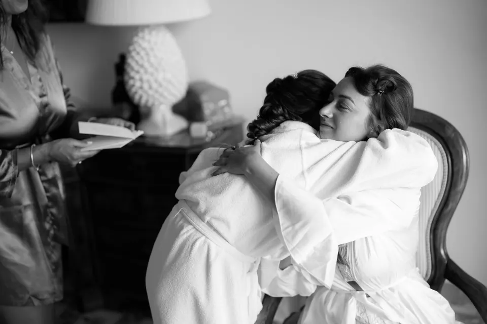 Bride hugging her bridesmaid while getting ready.