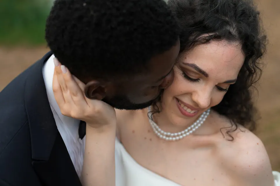 El novio besa el hombro de la novia en el patio de la villa.