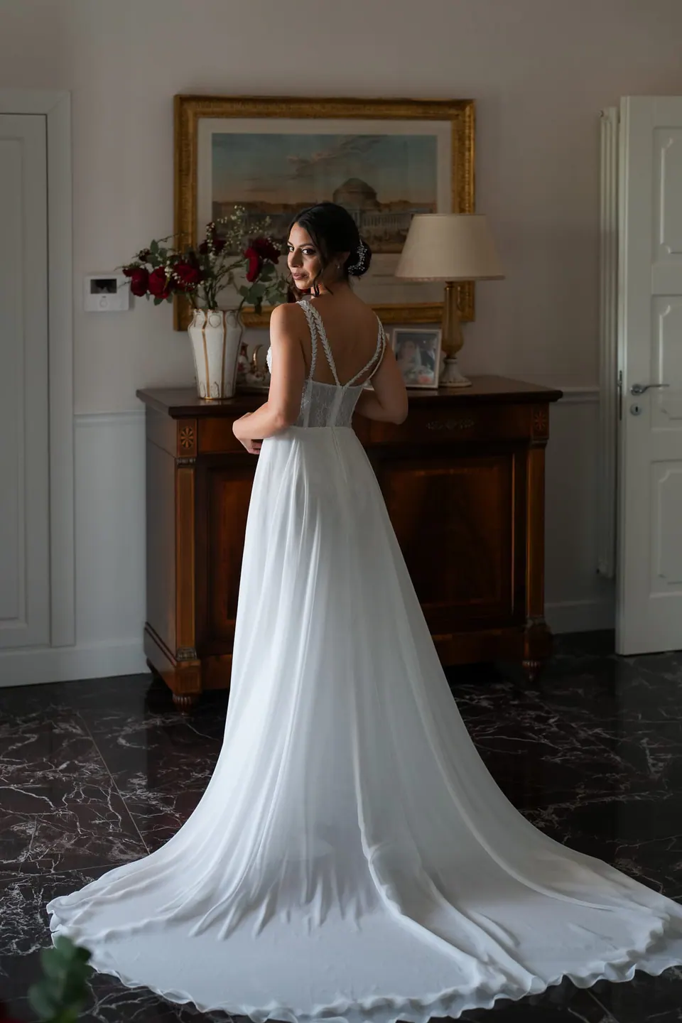 Bride inside Villa Angelina, the long train of her gown behind her.