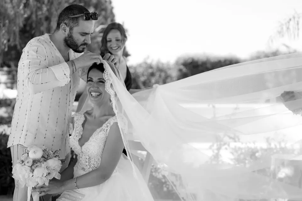 Black and white photo of the groom adjusting the bride's veil