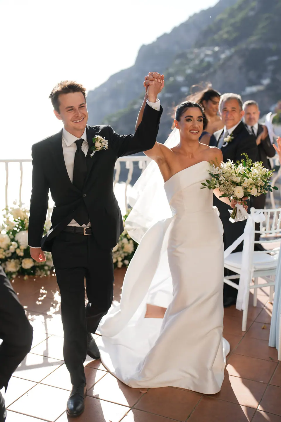 Groom raising his arm and the bride smiling as they leave the ceremony.