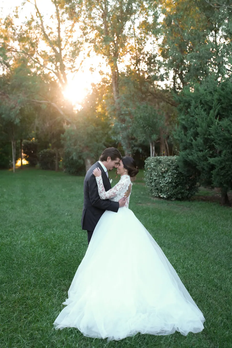 Bride and groom kissing on the lawn at sunset