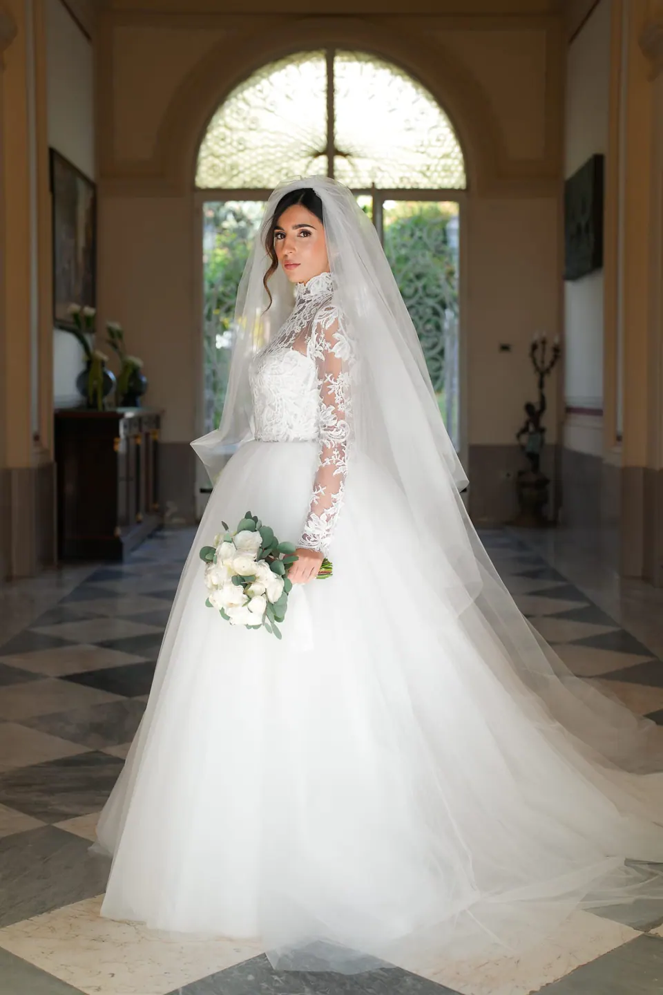 Bride entering the ceremony hall with her bouquet, golden light inside the villa.