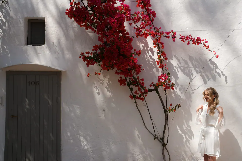 La novia bajo buganvillas de un rojo intenso en Apulia.