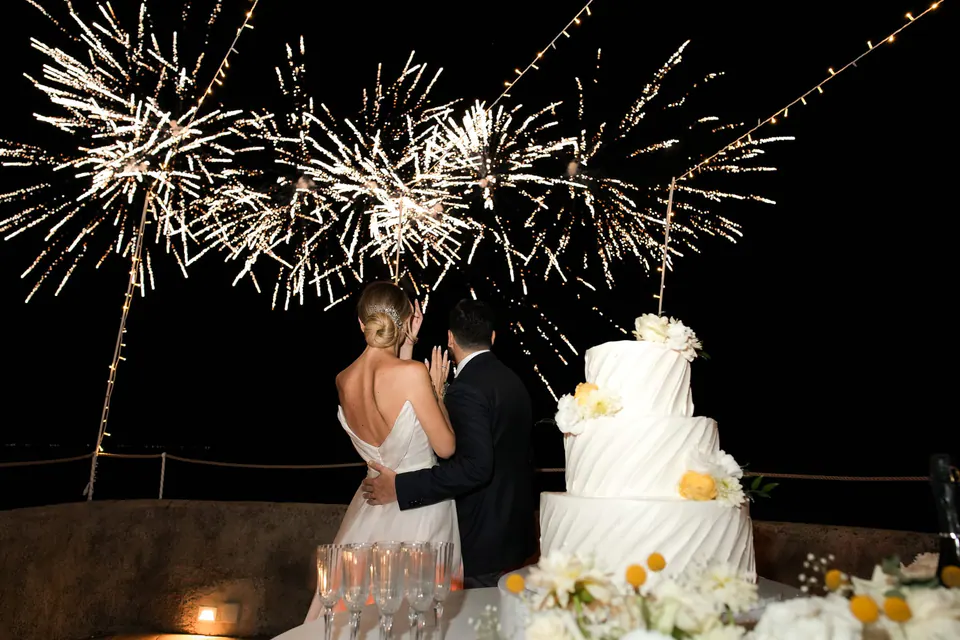 Das Brautpaar schneidet unter Feuerwerk im Torre La Cerniola die Torte an.
