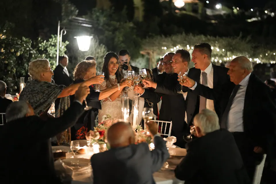 Dinner unter Lichterketten, Gäste mit Wein und Lachen im Panoramagarten.