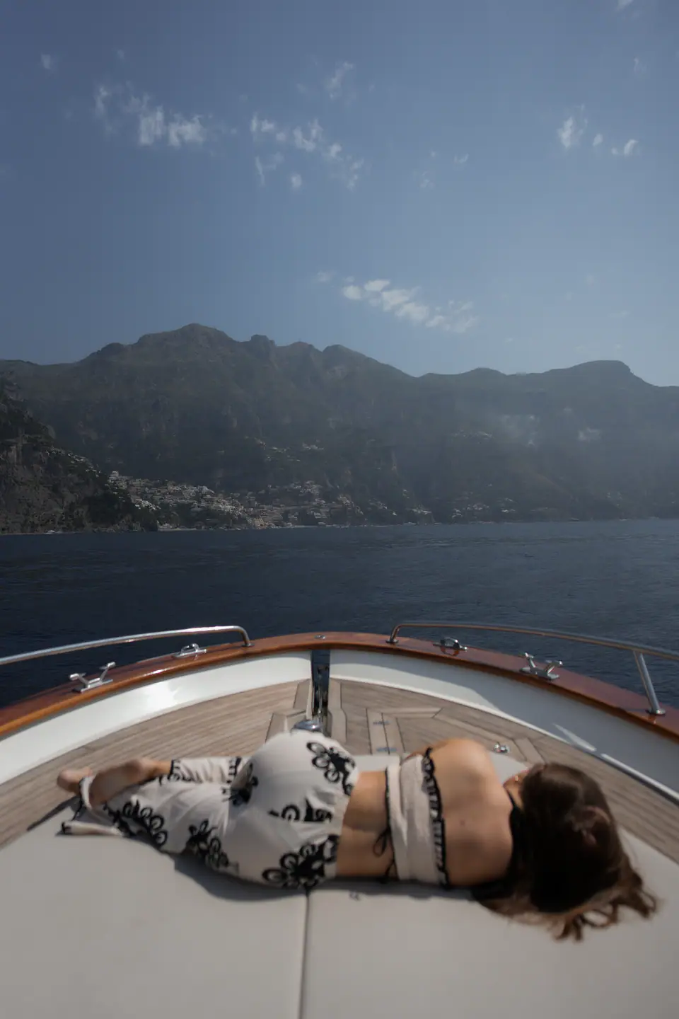 Sunbathing on the bow of the boat, the coast behind.