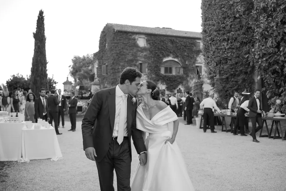 Foto in bianco e nero degli sposi nel cortile di Torre San Severino tra gli invitati.