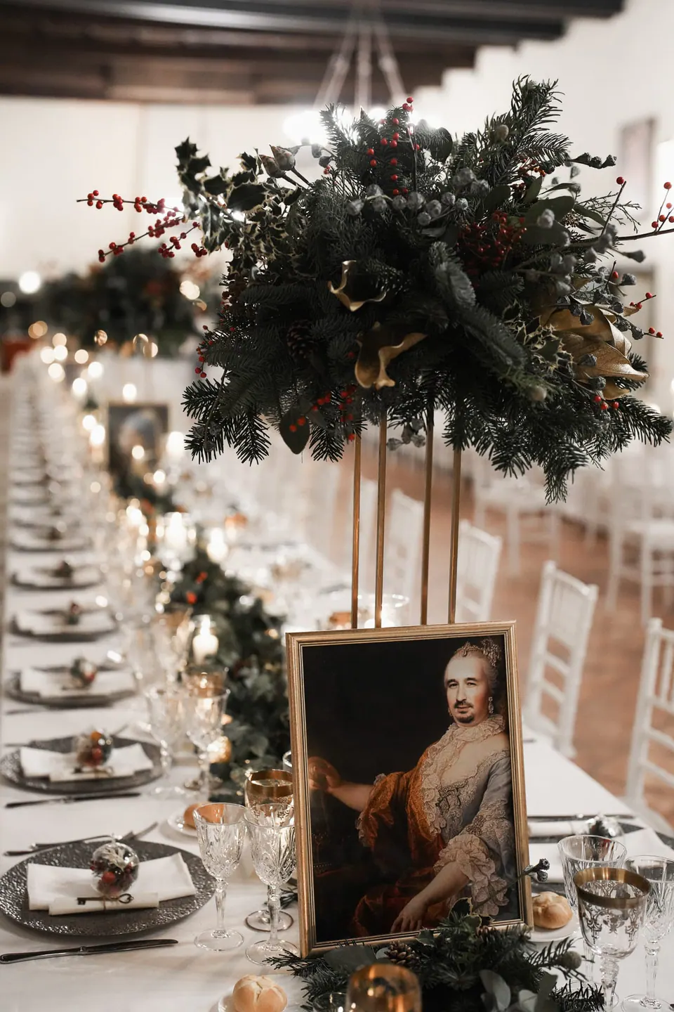 Long reception table with greenery centrepieces, candles and a framed portrait.