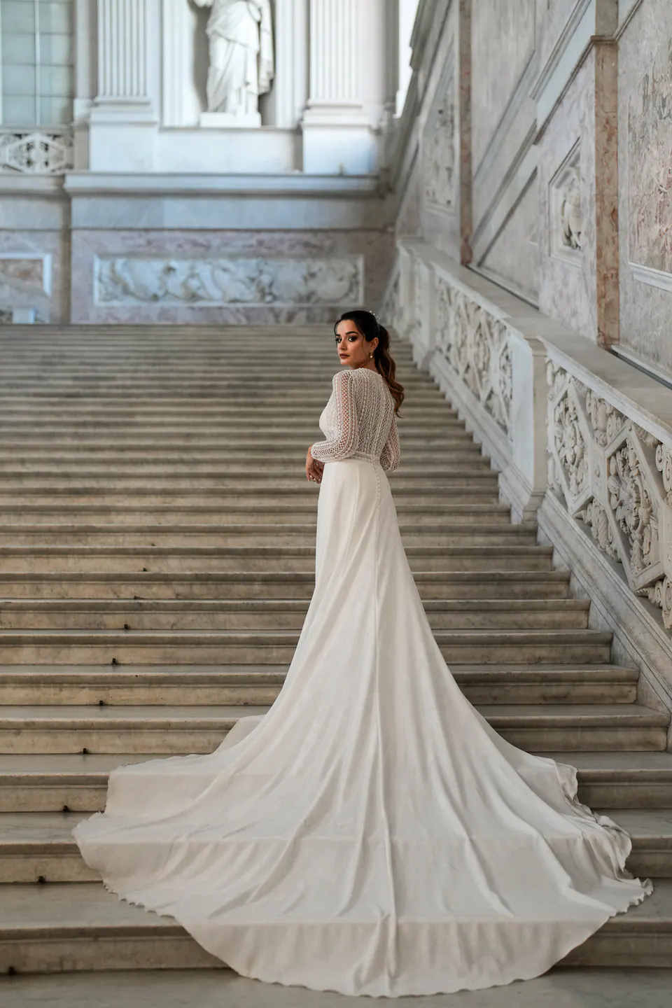 Bride on a monumental marble staircase in Naples, her long train spread on the steps.